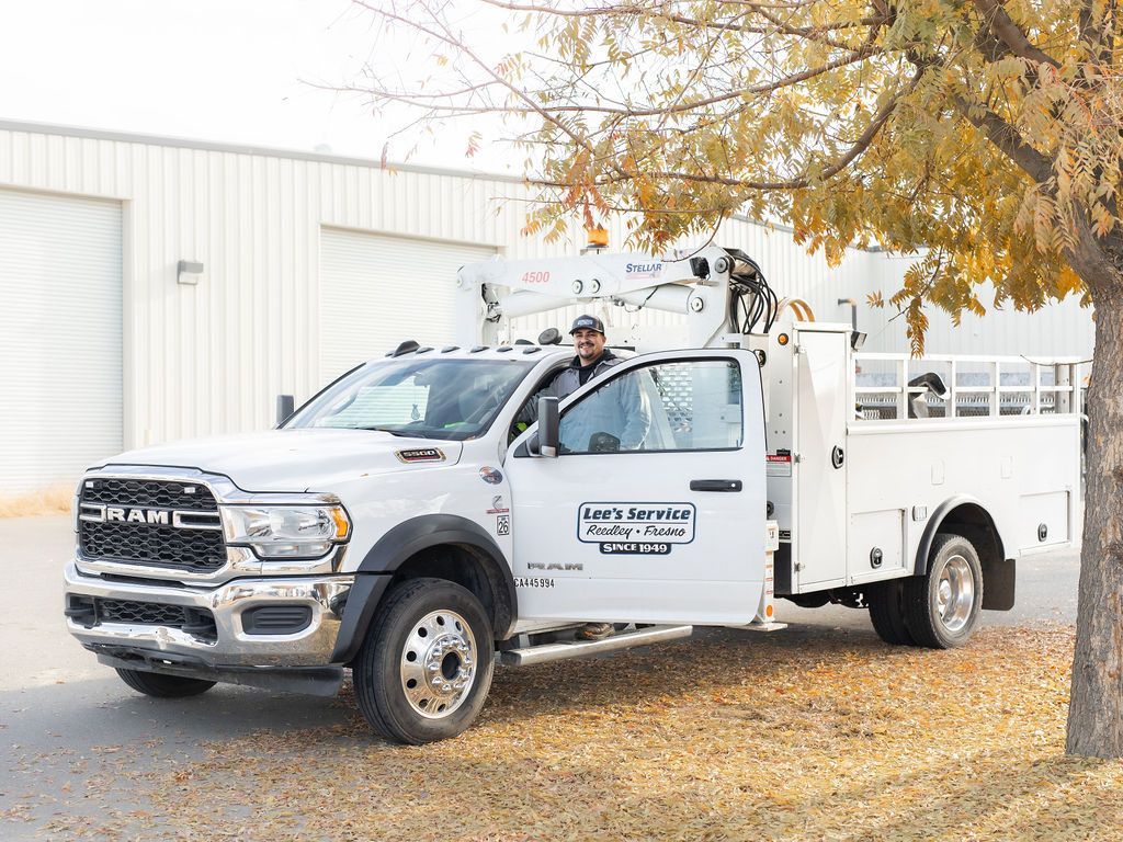 A man is standing in the doorway of a white utility truck.