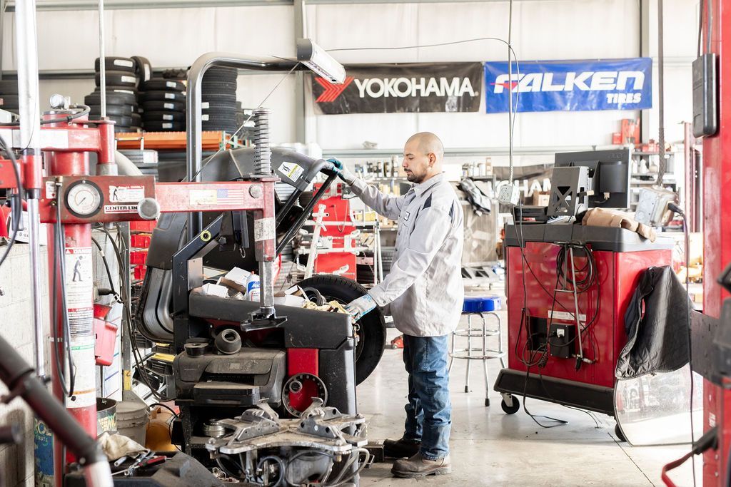 A man is working on a tire in a garage with a yokohama sign in the background
