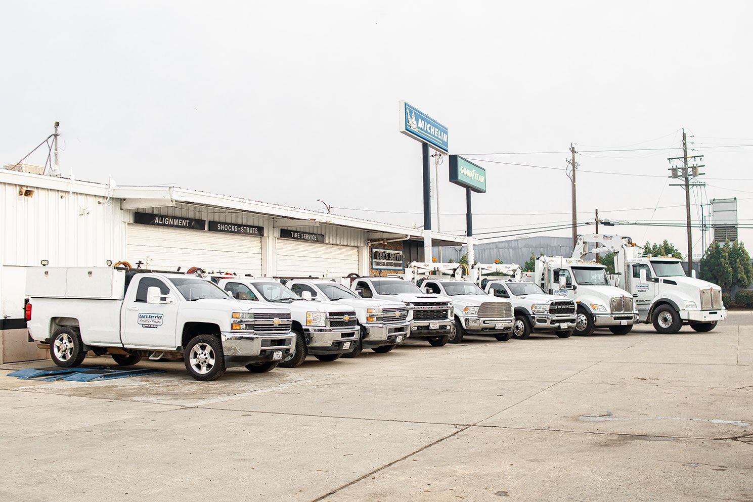 A row of white trucks are parked in front of a building that says castrol