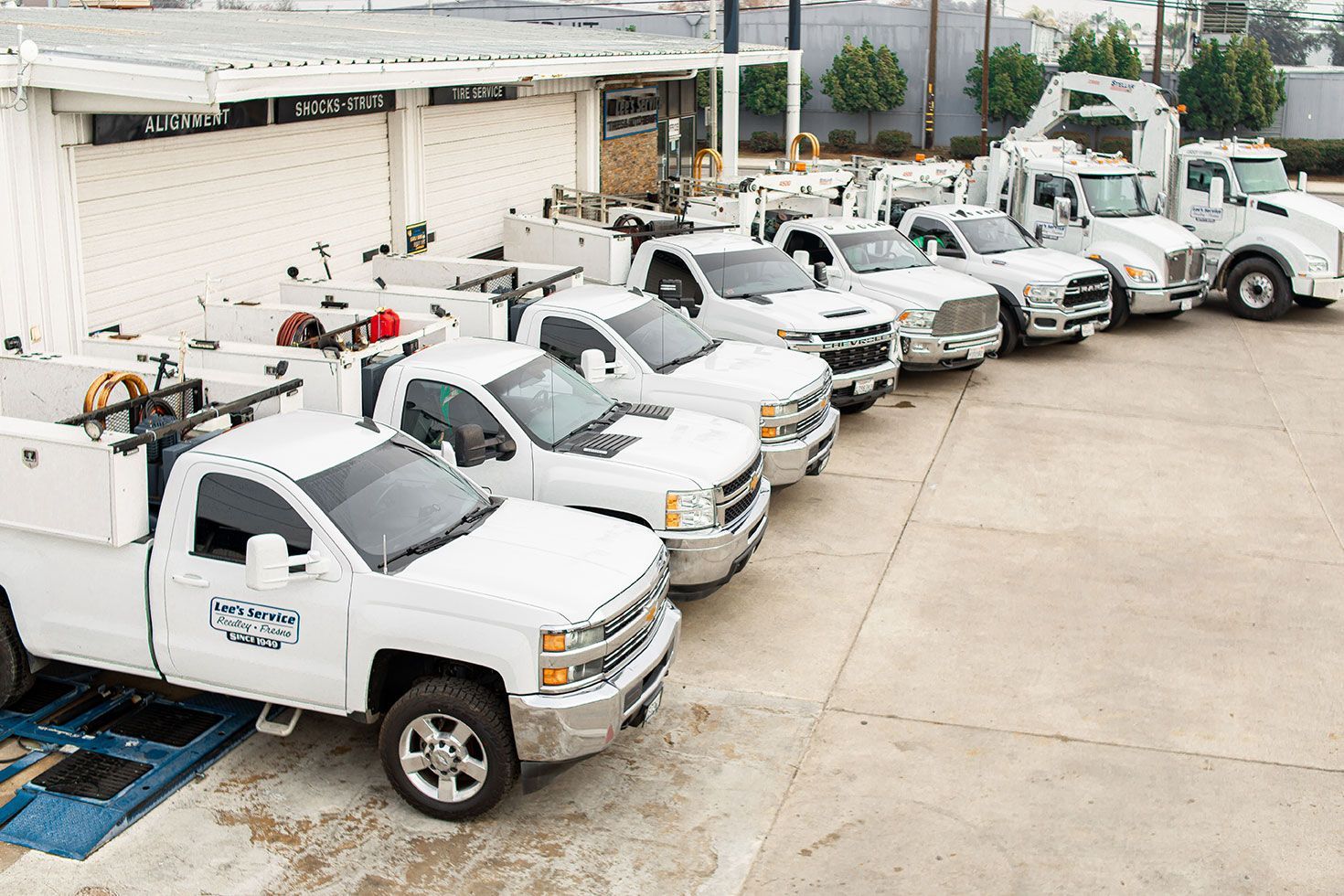 A row of white trucks are parked in front of a building