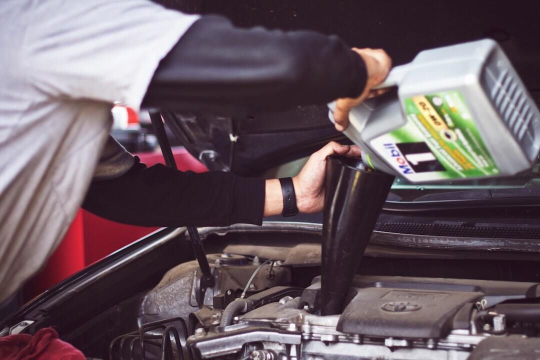 A man is pouring oil into a car engine.