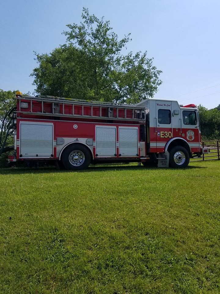 Firefighters training with a hose in a grassy field.