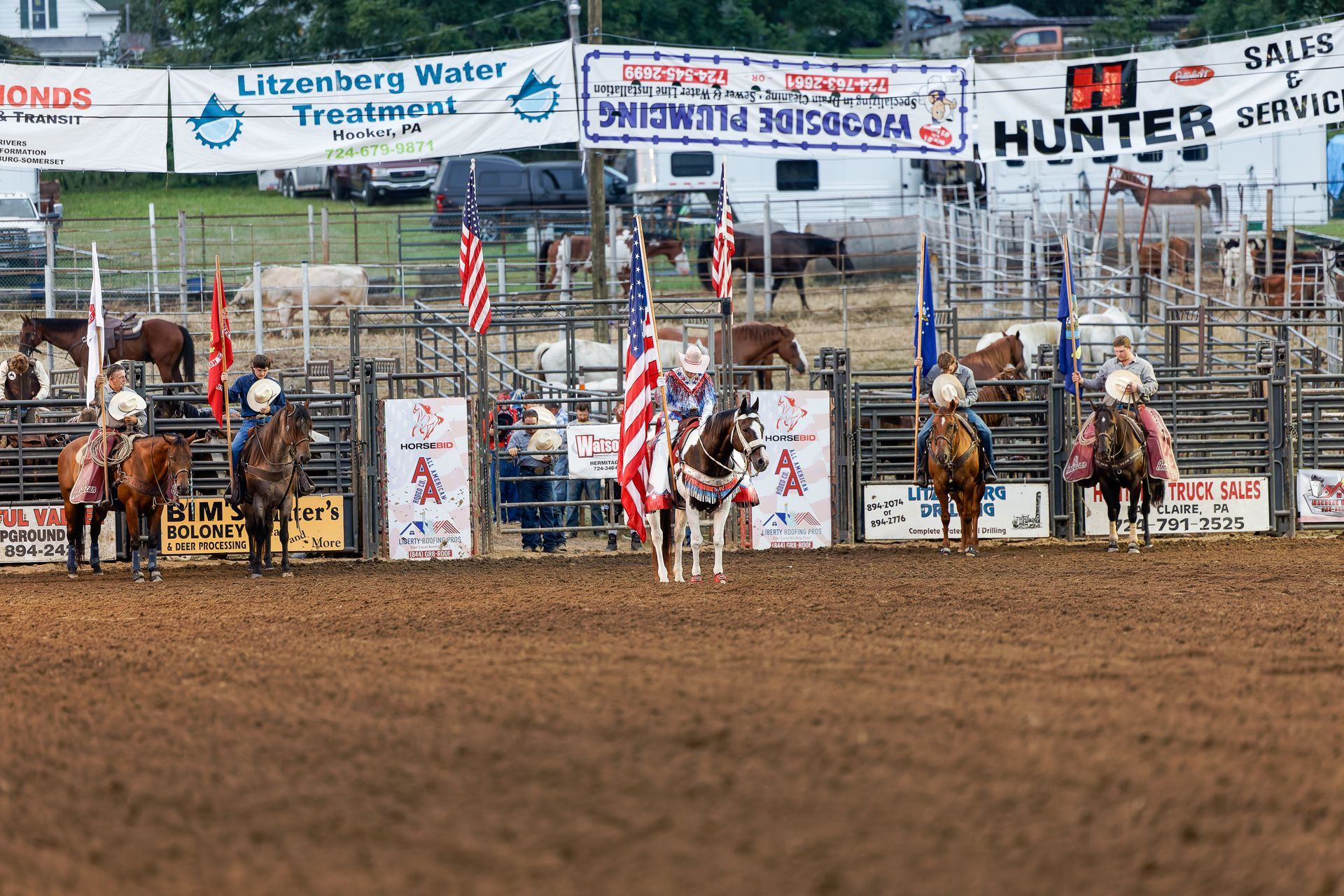 A group of people are riding horses in a rodeo arena.