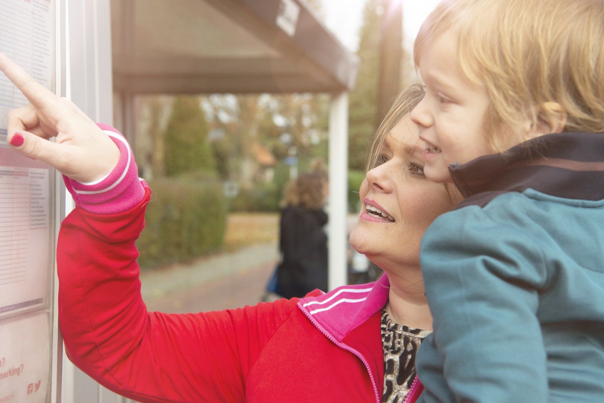 Vrouw wijst naar dienstregelingsabel op bord