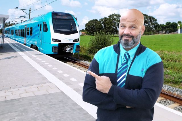 Machinist wijst op achtergrond naar trein Valleilijn.