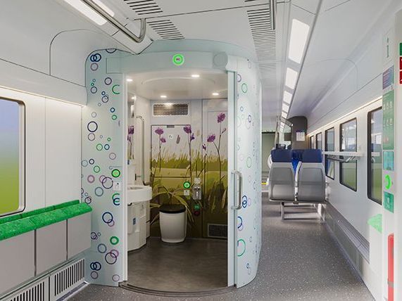Afbeelding van een gangpad in de trein met zicht op een geopende toilet. De buitenkant van het tolit heeft gekleurde bollen in paars, blauw en groen. De binnenwand van de toilet heeft een illustratie van de blauwgraslanden van de Gelderse Vallei
