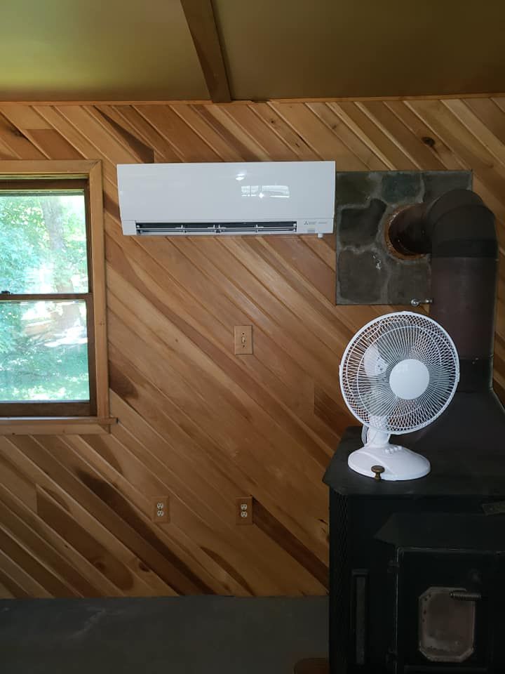 A room with wood paneling , a fan , and a window.
