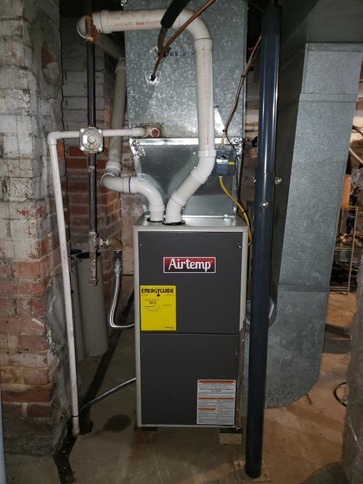 An air conditioner is installed in a basement next to a brick wall.