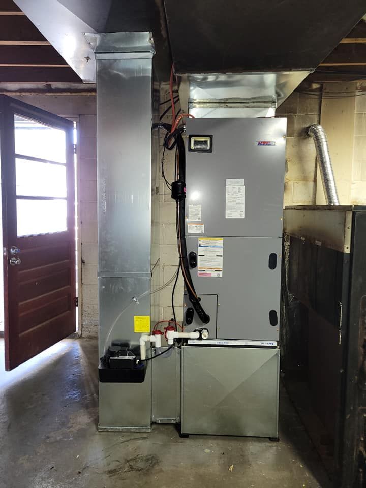 A large air conditioner is sitting in a basement next to a door.