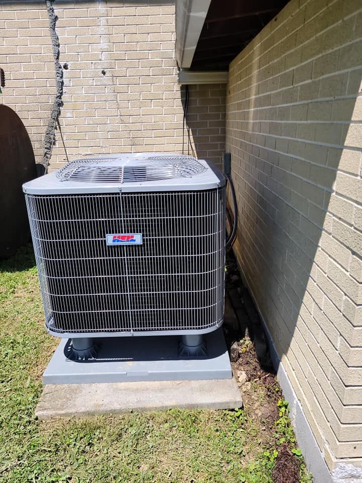 A large air conditioner is sitting on the side of a brick building.