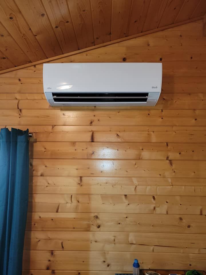A white air conditioner is hanging on a wooden wall in a room.