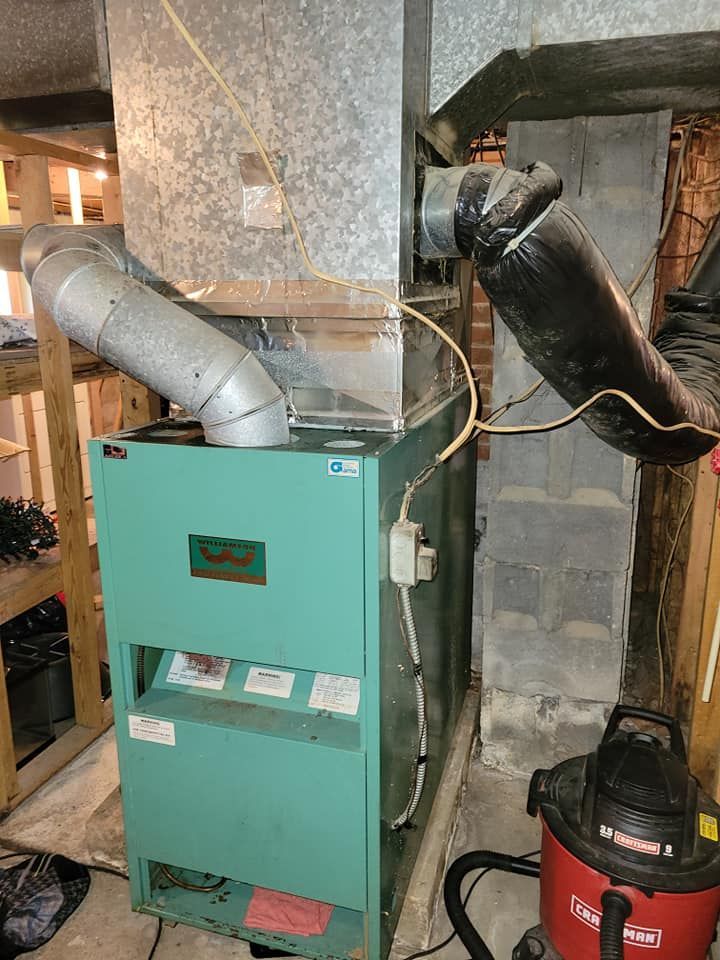 A green heater is sitting in a basement next to a vacuum cleaner.