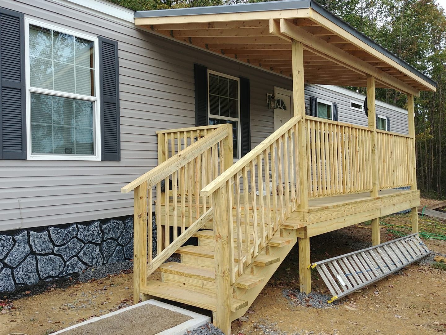 A mobile home with a wooden deck and stairs.