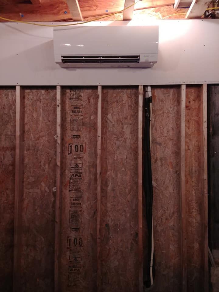 A wall mounted air conditioner is hanging on a wooden wall.