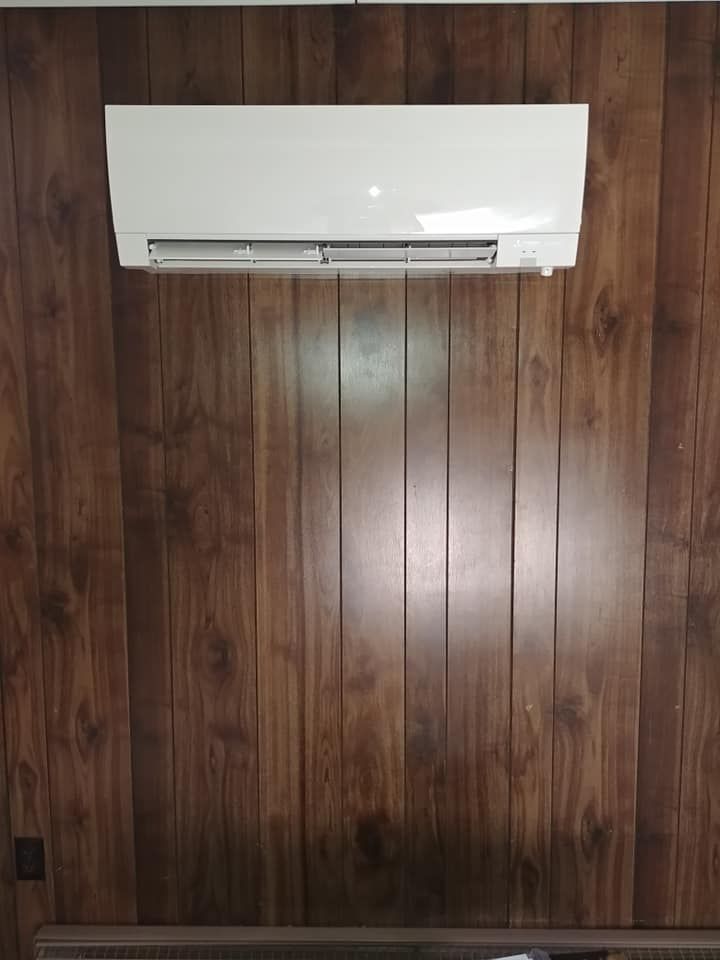 A white air conditioner is hanging on a wooden wall.