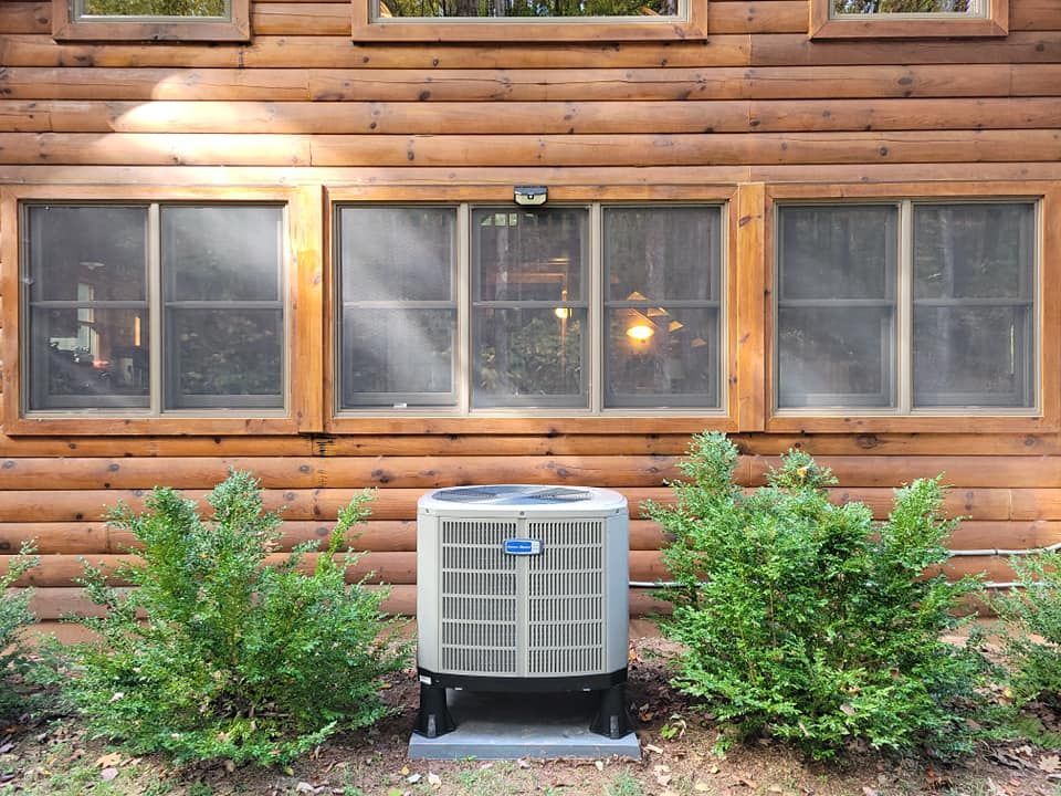 An air conditioner is sitting outside of a log cabin
