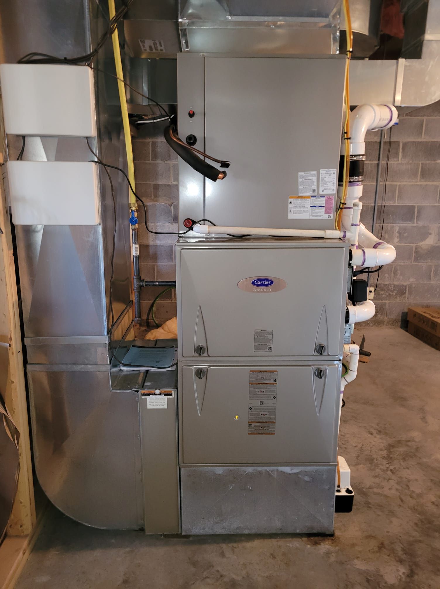 An air conditioner is sitting in a basement next to a brick wall.