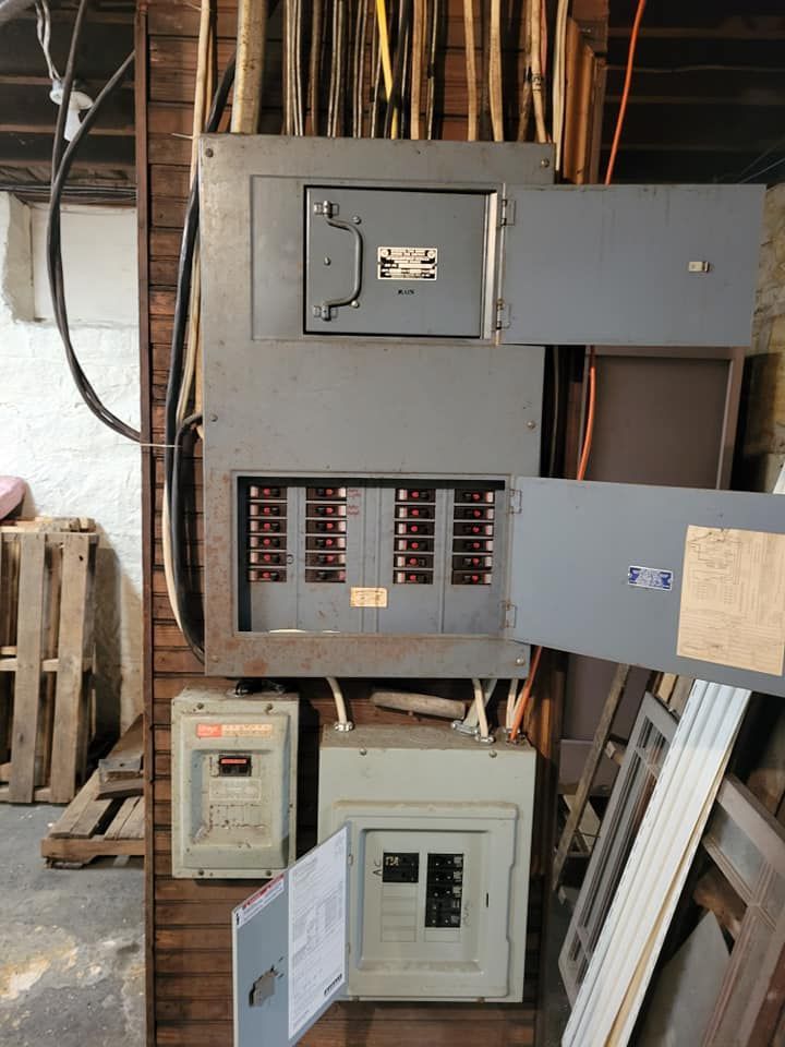 A electrical box with the door open is sitting on a wooden wall.