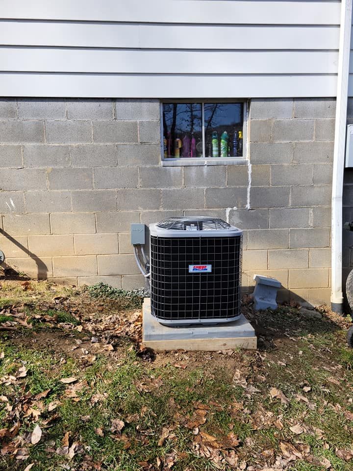 An air conditioner is sitting outside of a brick building next to a window.