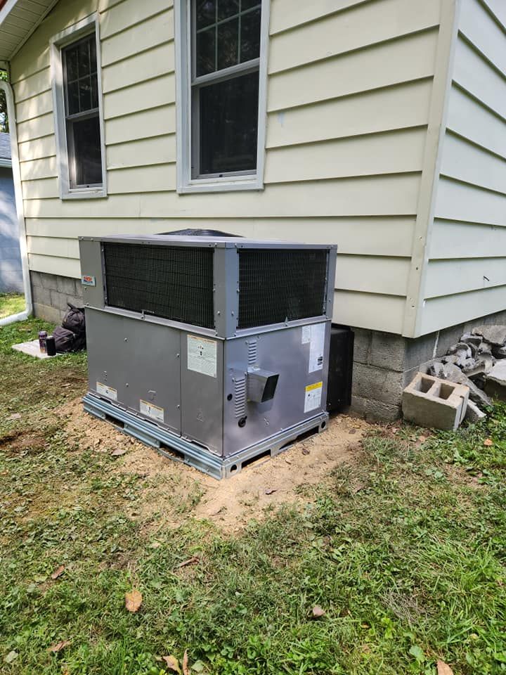 A large air conditioner is sitting in the backyard of a house.