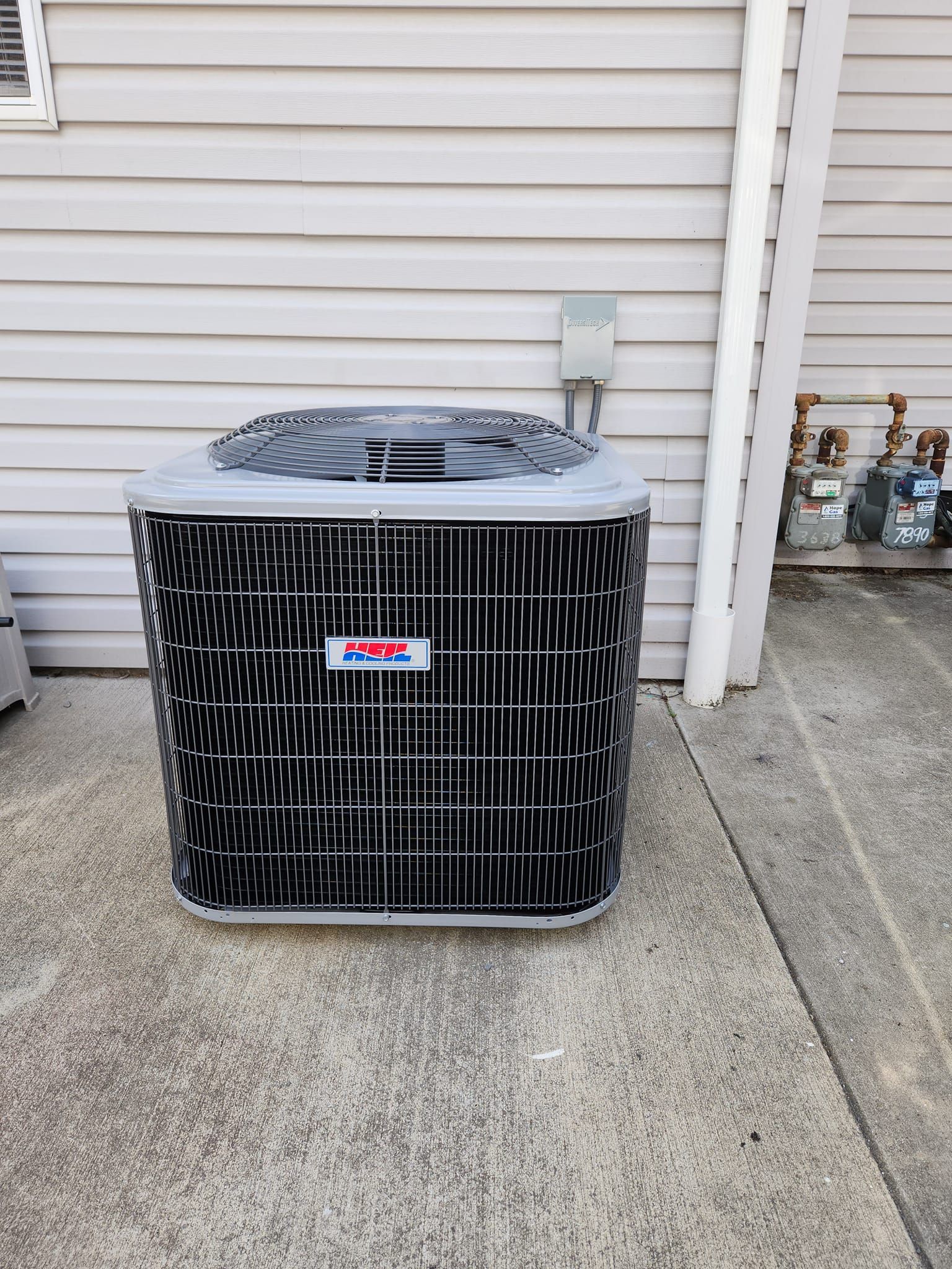 An air conditioner is sitting on the sidewalk in front of a house.