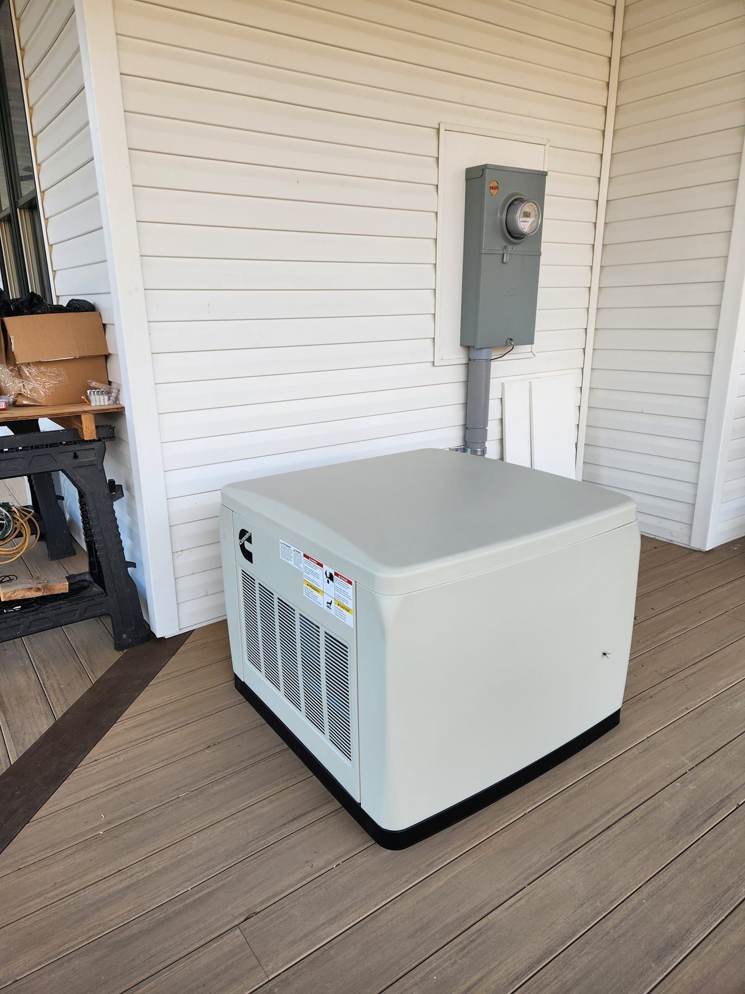 A white box is sitting on a wooden deck next to a white wall.