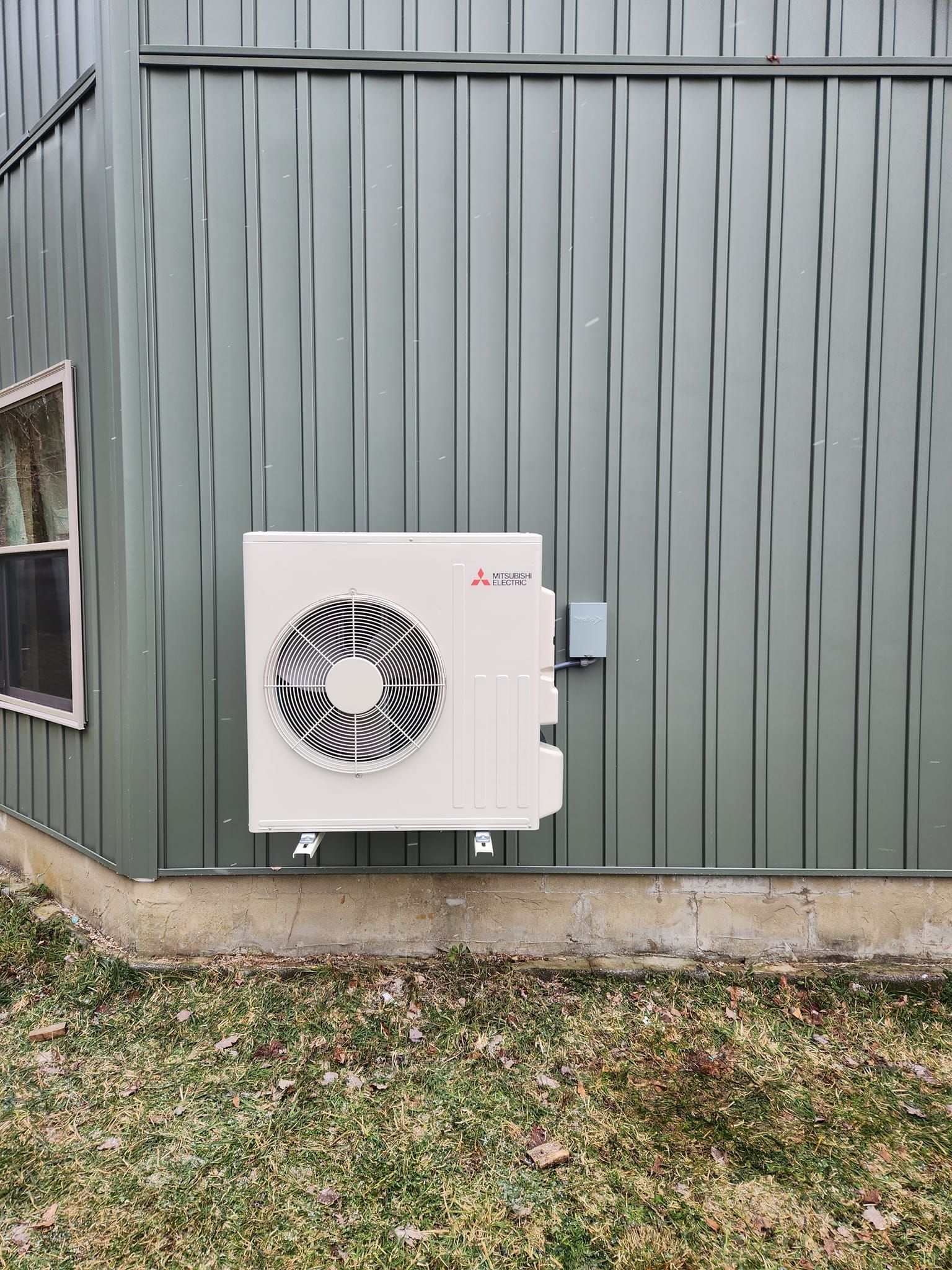 A white air conditioner is mounted on the side of a building.