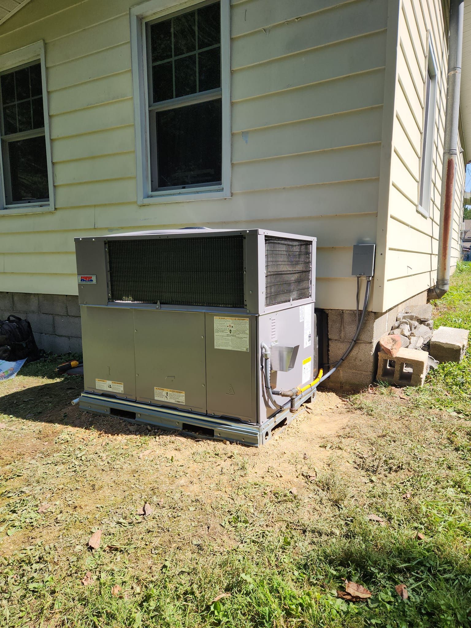 A large air conditioner is sitting on the side of a house.