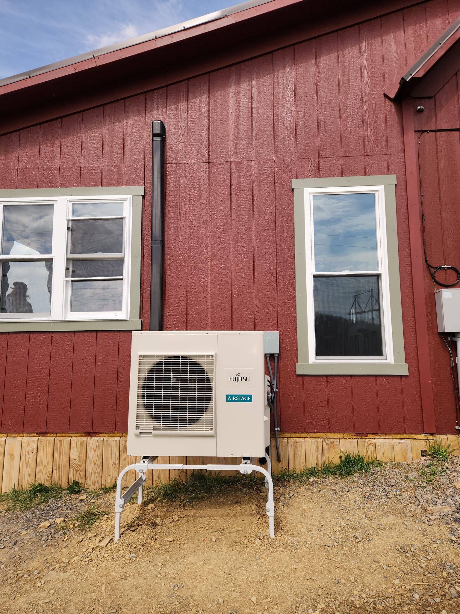 A red house with a white air conditioner on the side of it.