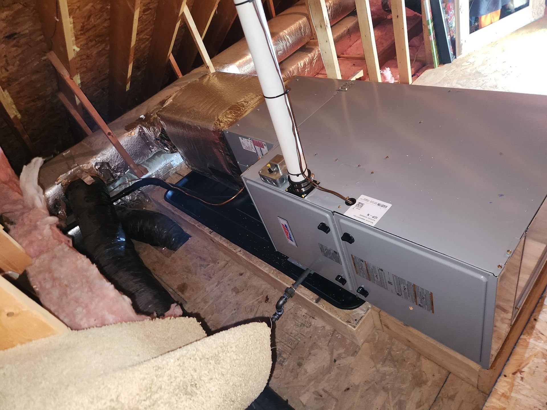 An air conditioner is sitting in the attic of a house.
