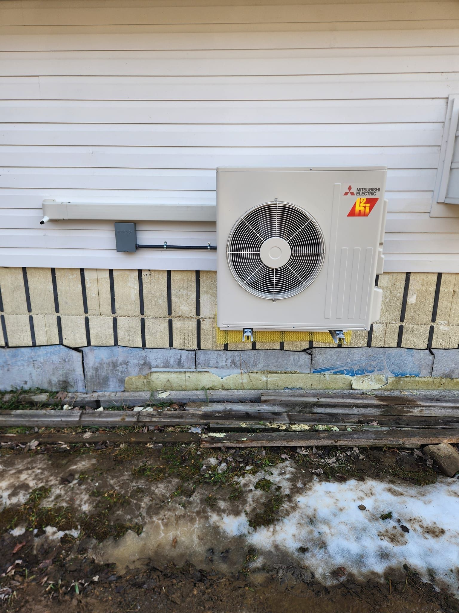 A mitsubishi air conditioner is installed on the side of a house.