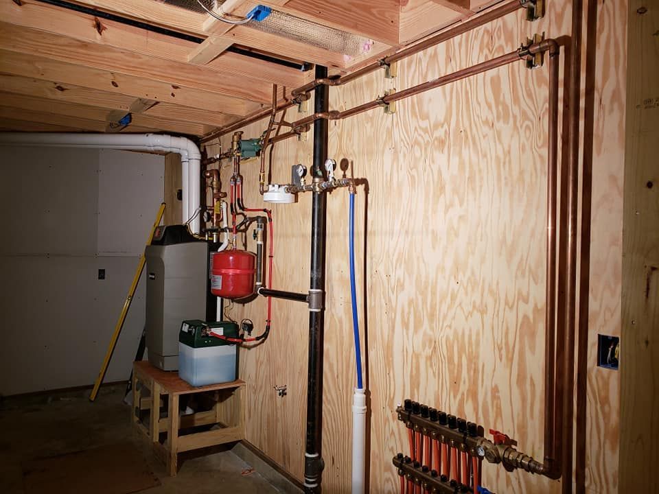 A room with a lot of pipes and a heater in it.