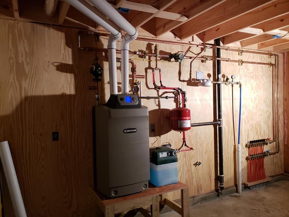 A boiler is sitting on top of a wooden table in a basement.