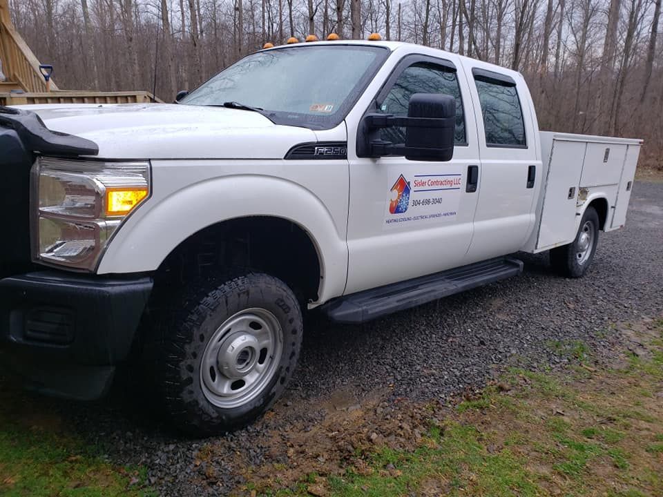 A white truck with a utility bed is parked on a gravel road.