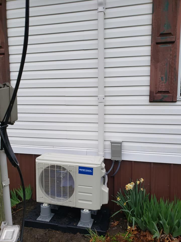 A white air conditioner is sitting on the side of a house.