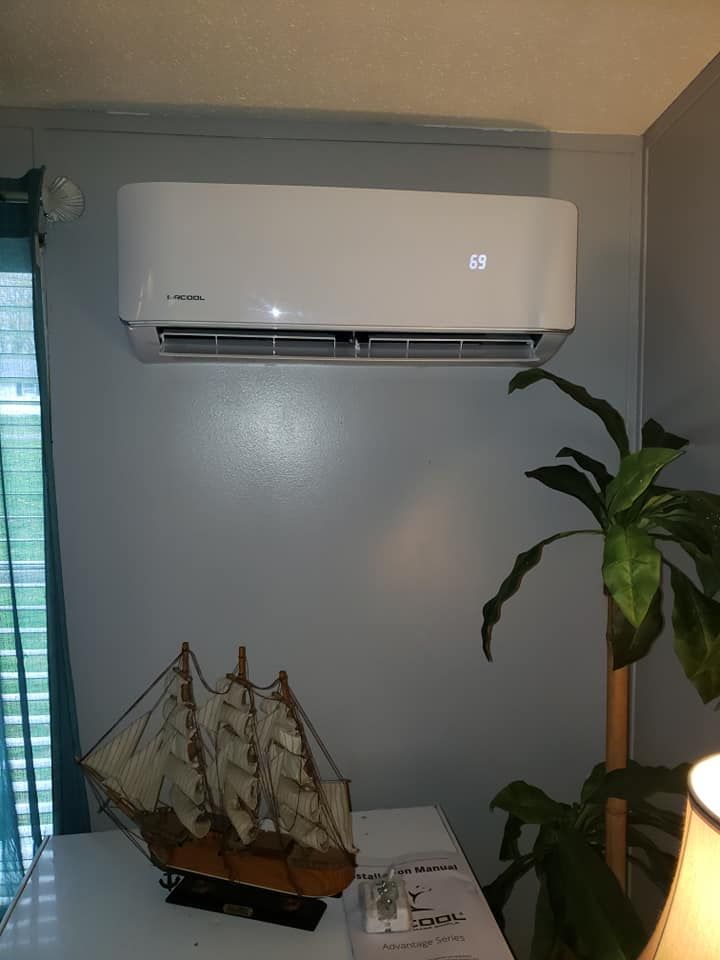 A white air conditioner is hanging on a wall in a living room.
