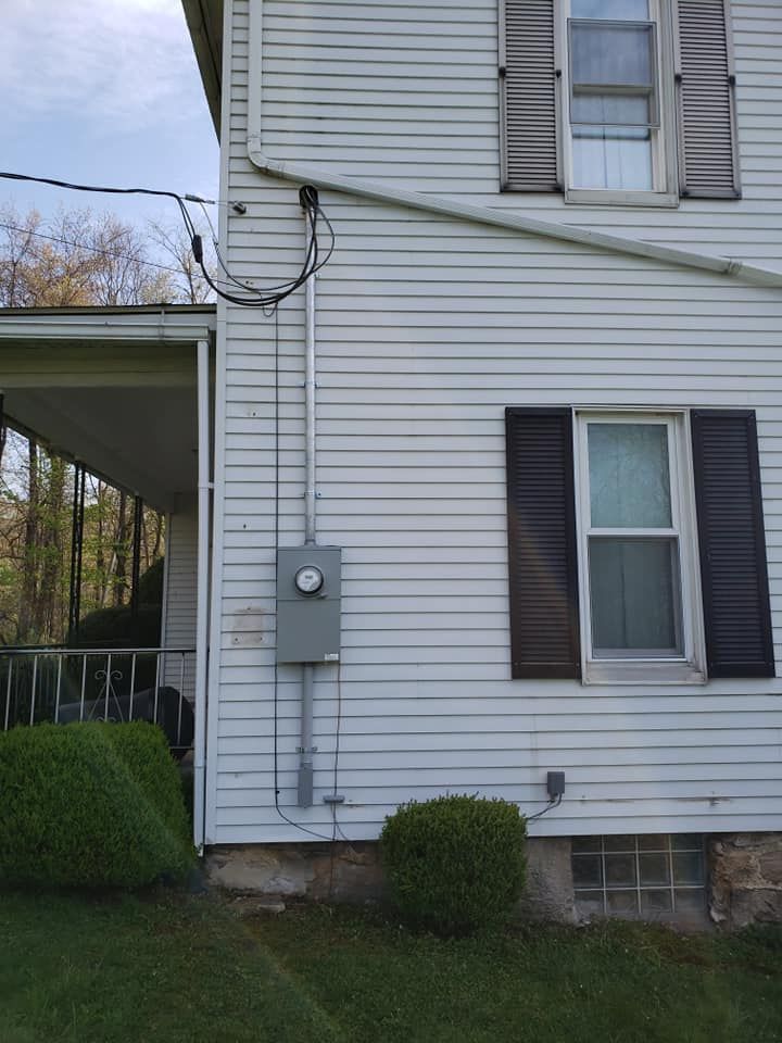 A white house with black shutters and a box on the side of it.