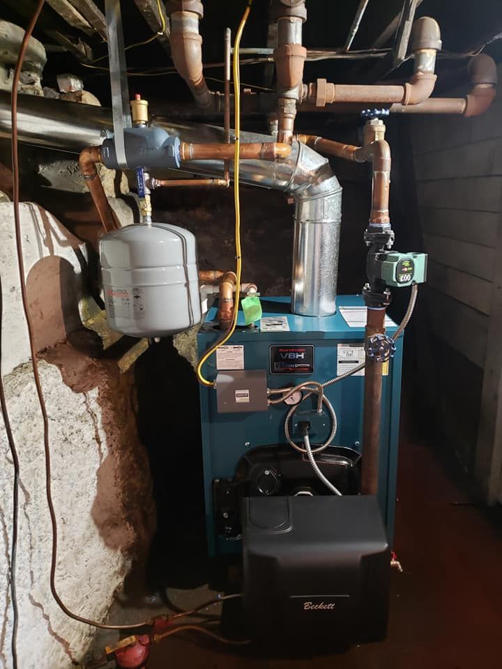 A blue boiler is sitting in a basement next to a wall.