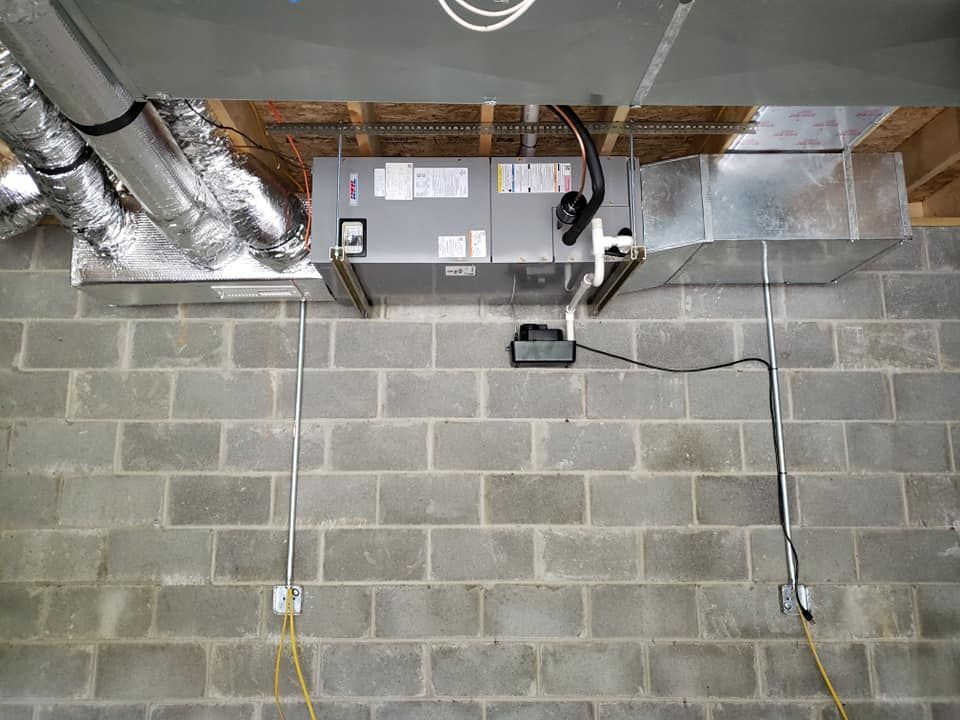 An air conditioner is mounted on a brick wall in a basement.