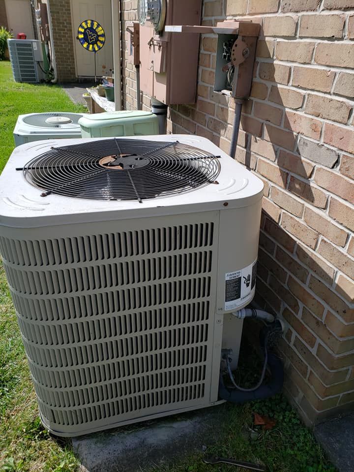 A large air conditioner is sitting on the side of a brick building.