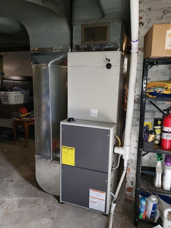An air conditioner is sitting in a basement next to a fire extinguisher.