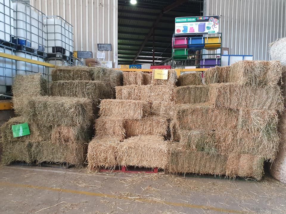 A Bunch Of Hay Bales Are Stacked On Top Of Each Other In A Warehouse — Maleny Hardware & Rural Supplies In Maleny, QLD