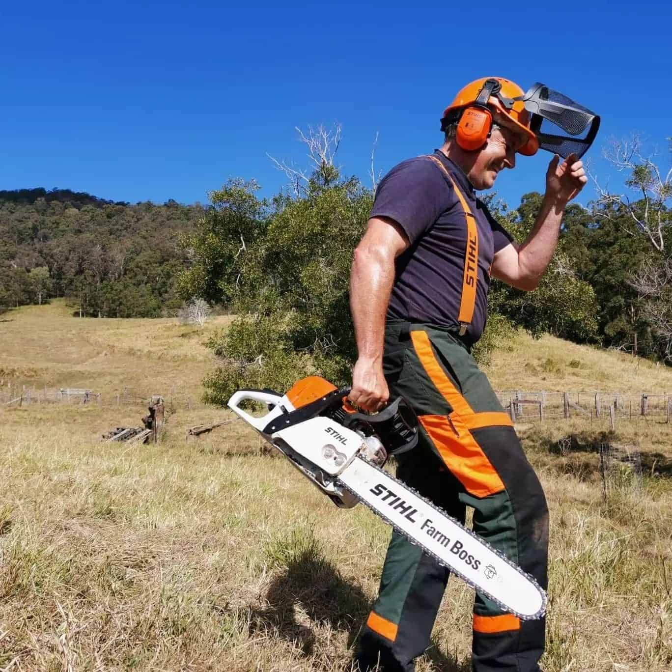 A Man Carrying A Stihl Chainsaw In A Field — Maleny Hardware & Rural Supplies In Maleny, QLD