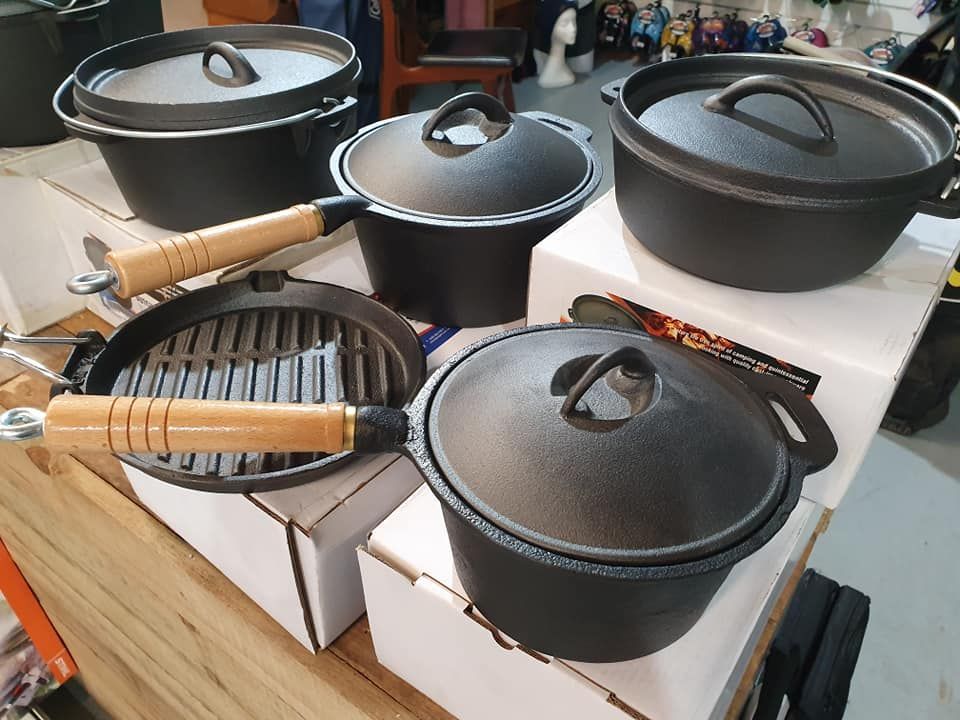 A Group Of Cast Iron Pots And Pans Sitting On Top Of A Wooden Table — Maleny Hardware & Rural Supplies In Maleny, QLD