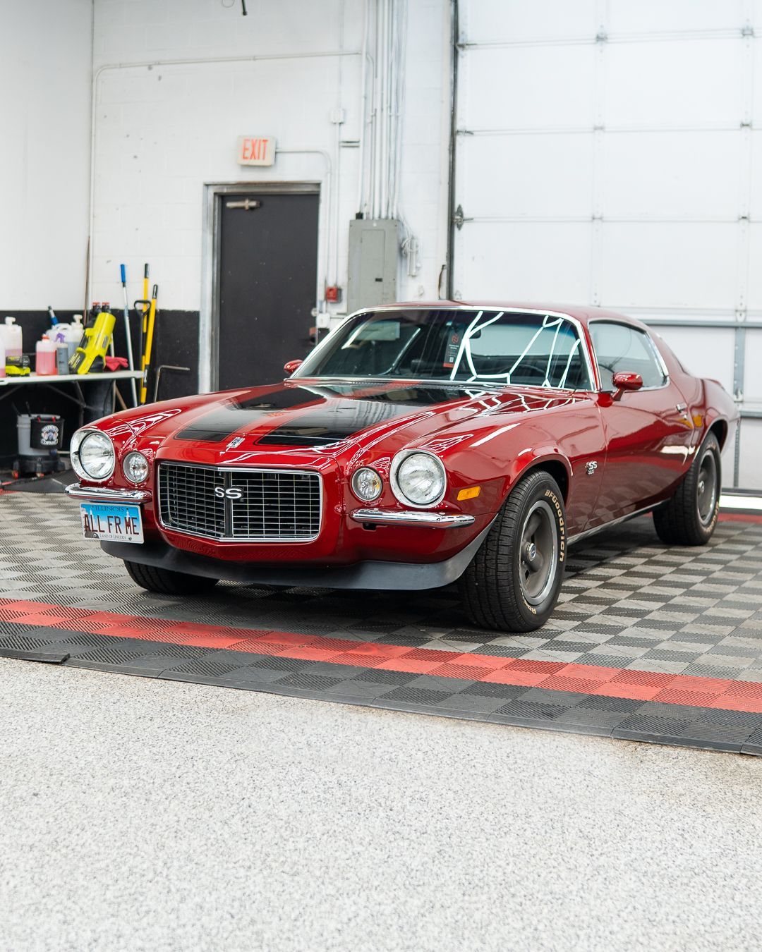 Red classic sports car displayed indoors on a checkered floor.