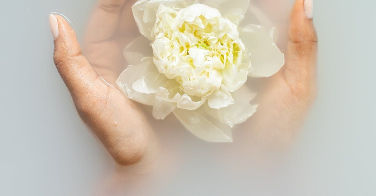 A woman is holding a white flower in her hands in a bathtub.