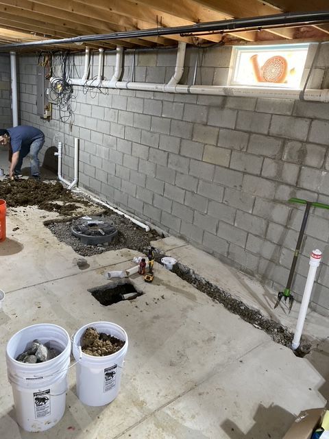 A man is digging a hole in the floor of a basement.