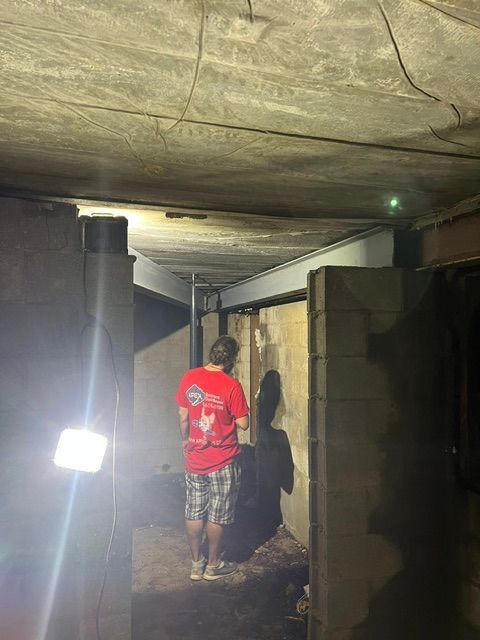 A man in a red shirt is standing in a dark room.