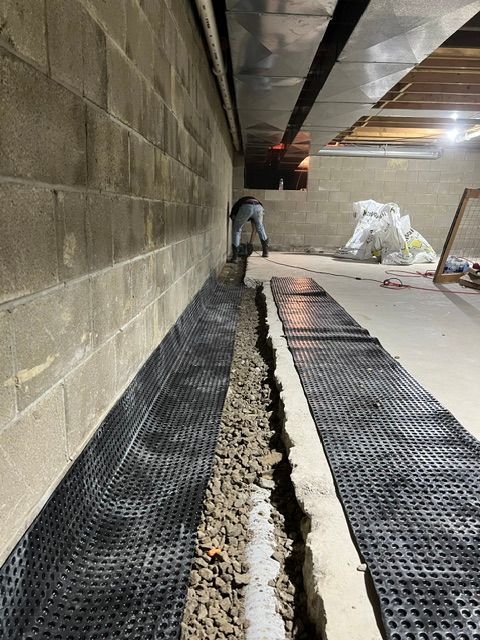 A man is standing next to a brick wall in a basement.