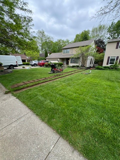 A man is cutting grass in front of a house.